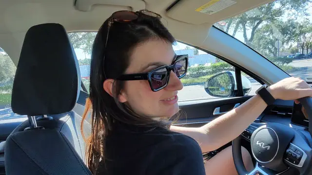 Camila, da Desenrola, ao volante de um carro alugado em Orlando, de óculos escuros e sorrindo