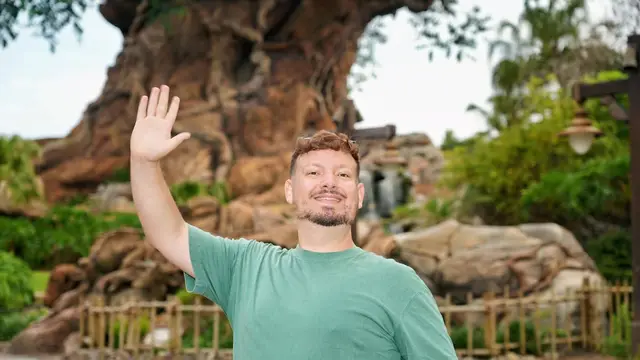 Thomaz acena diante da base da Árvore da Vida, símbolo do Animal Kingdom, num dia claro