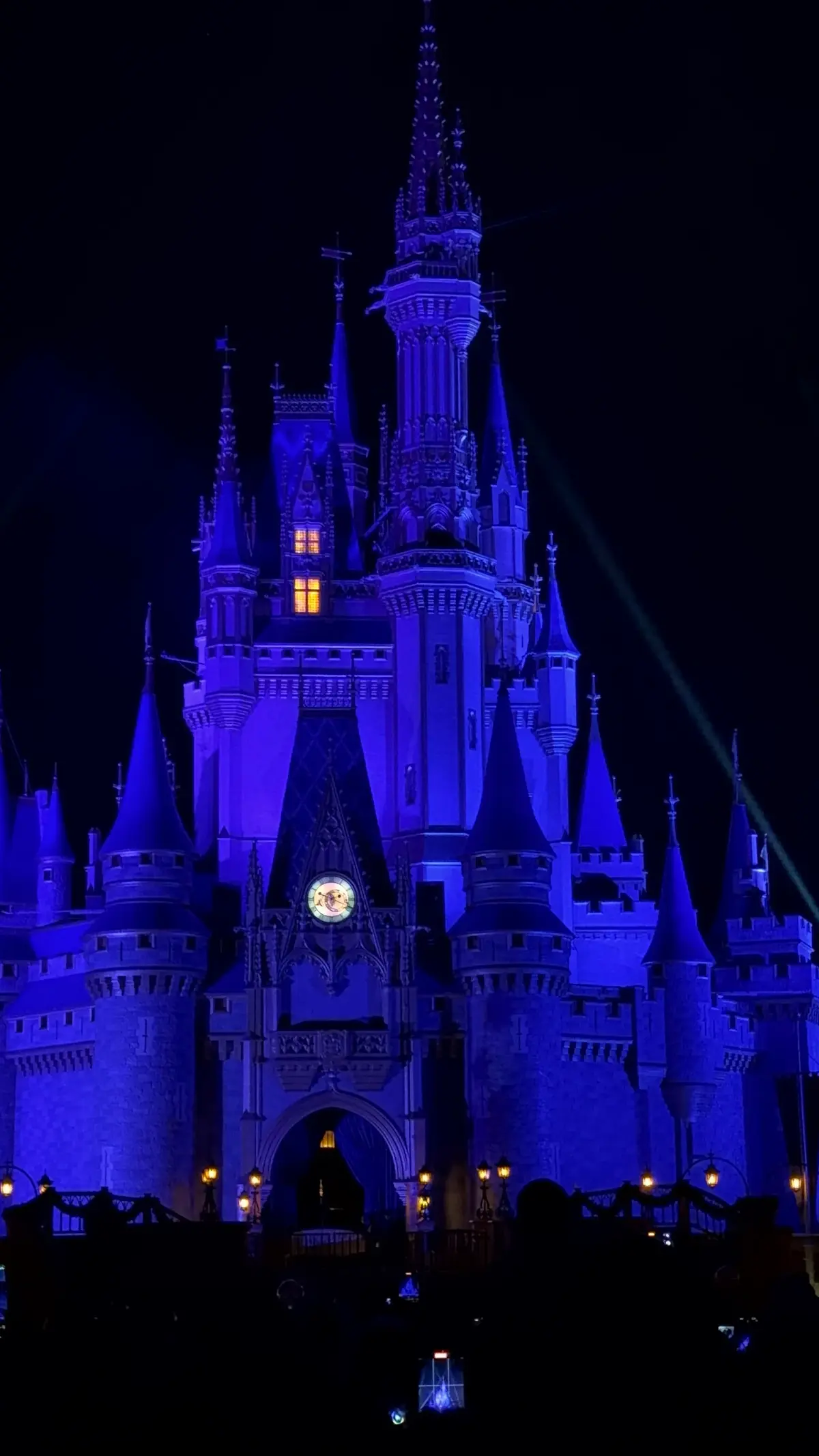 Castelo da Cinderela iluminado de azul e roxo à noite, no fim do dia de parque no Magic Kingdom