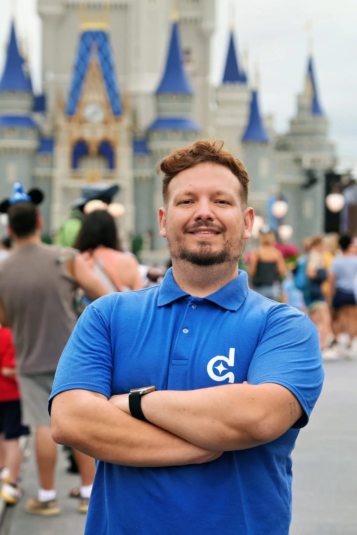 Thomaz, guia da Desenrola, de braços cruzados com a camisa da marca diante do Castelo da Cinderela, no Magic Kingdom