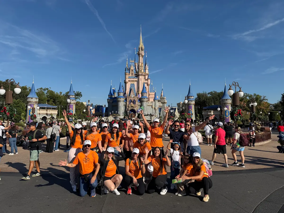 Grupo de viagem da Desenrola, de camisetas laranja, reunido diante do Castelo da Cinderela, no Magic Kingdom
