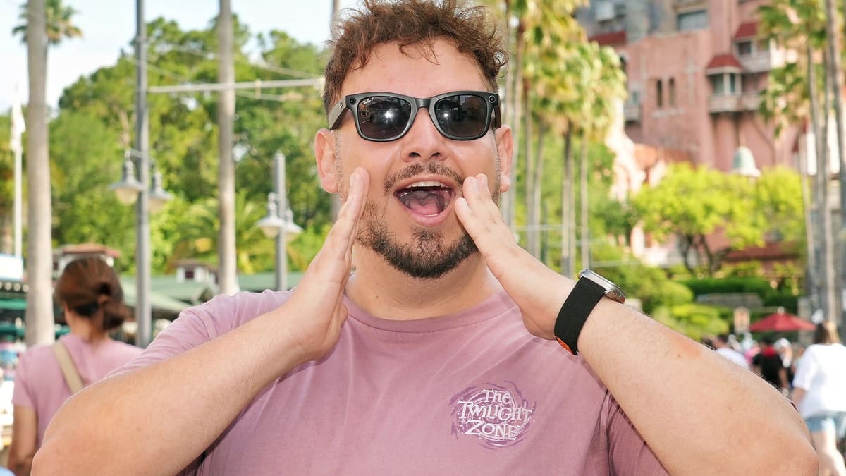Thomaz, guia da Desenrola, com as mãos na boca como quem chama o grupo, diante da Tower of Terror
