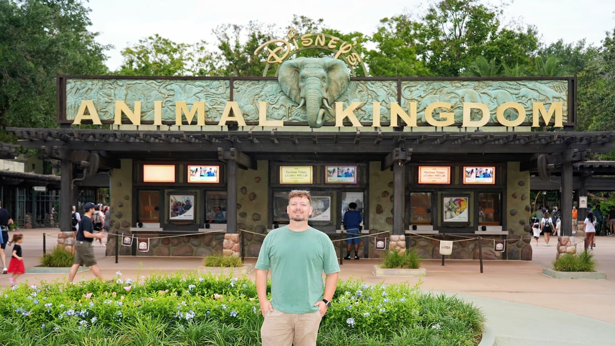 Thomaz em frente ao letreiro e às bilheterias da entrada do Animal Kingdom, parque da Disney em Orlando