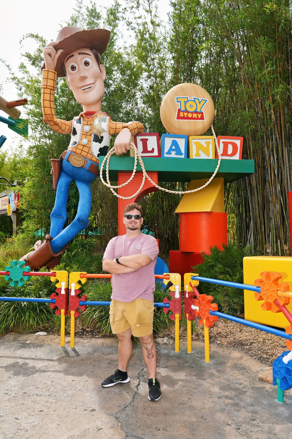 Thomaz de braços cruzados na entrada da Toy Story Land, ao lado do Woody gigante, no Hollywood Studios