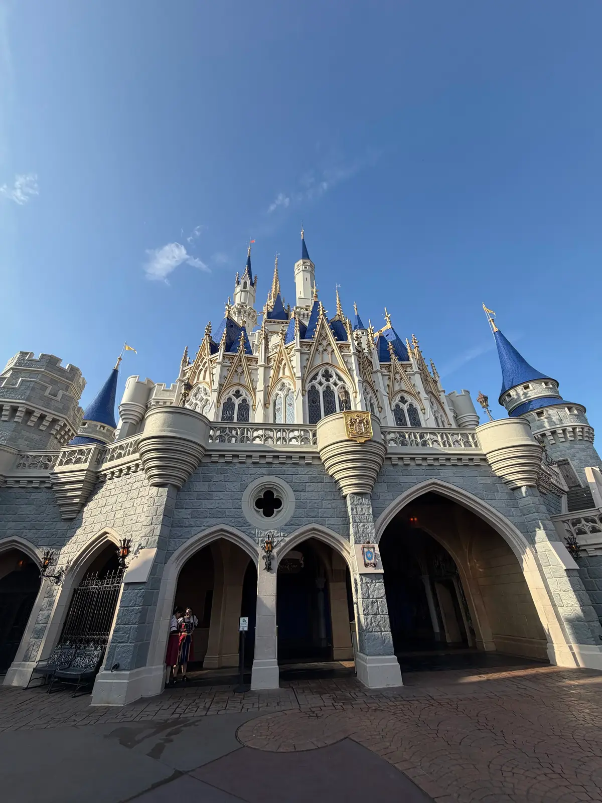 Castelo da Cinderela sob céu azul, com a praça quase vazia, no Magic Kingdom