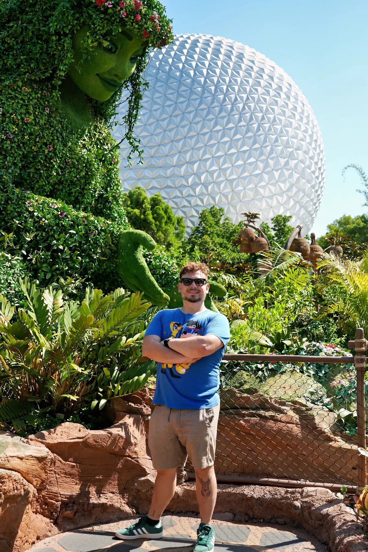 Thomaz de braços cruzados diante da topiaria de Te Fiti e da Spaceship Earth, no festival Flower & Garden do EPCOT