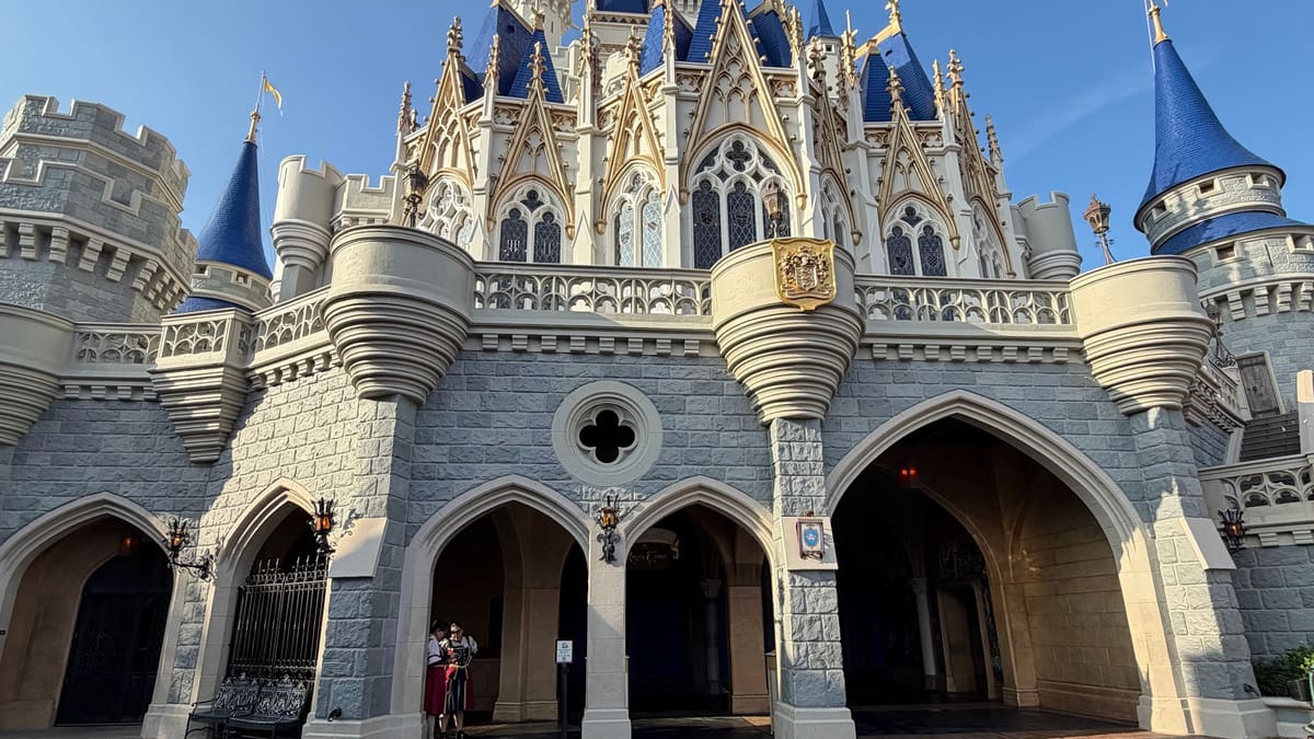 Castelo da Cinderela sob céu azul, com a praça da frente vazia, em foto grande-angular no Magic Kingdom