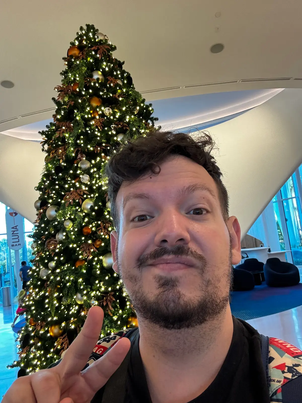 Thomaz faz sinal de paz diante da árvore de Natal no saguão de um hotel em Orlando