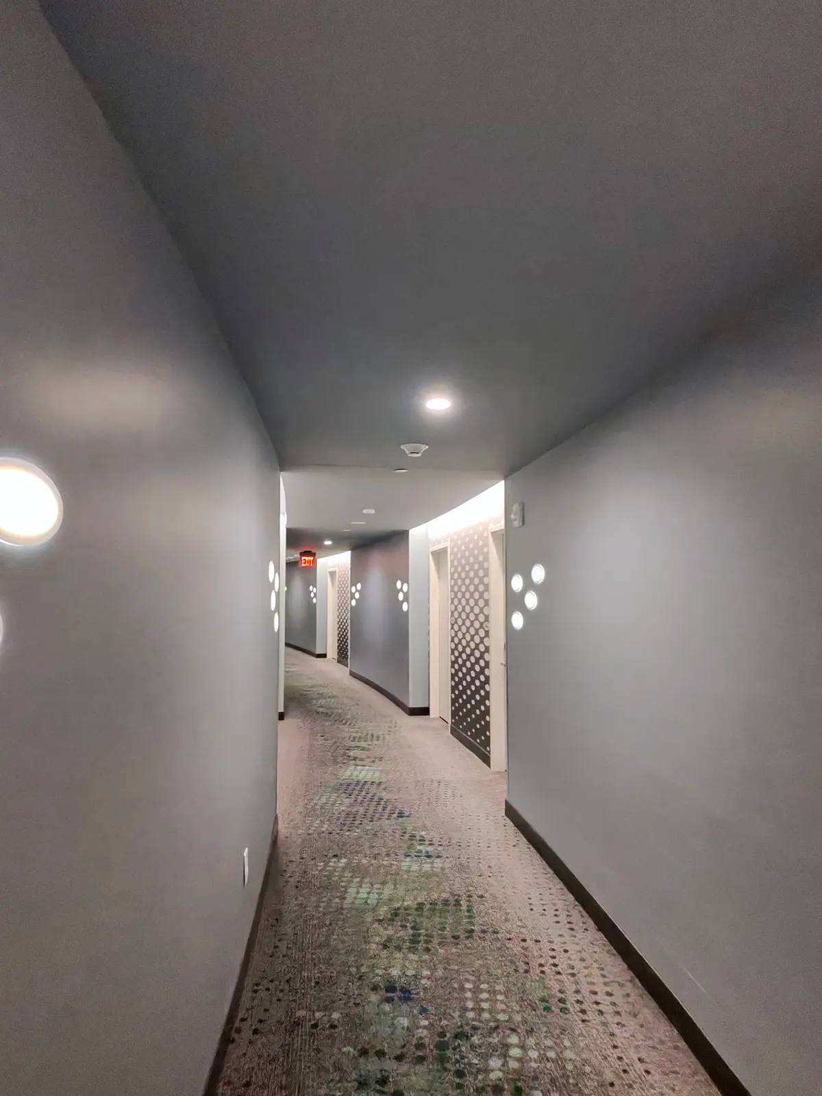 Corredor de quartos de um hotel em Orlando, com carpete estampado e luminárias redondas nas paredes