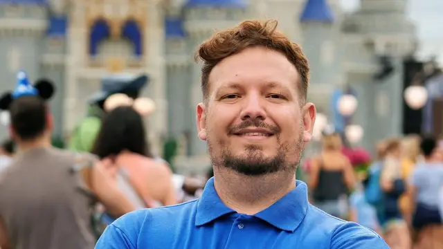 Thomaz, da Desenrola, de braços cruzados na Main Street do Magic Kingdom, com o castelo desfocado ao fundo
