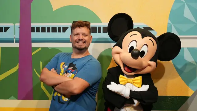 Thomaz de braços cruzados ao lado do Mickey, que imita a pose, no encontro com personagens do EPCOT