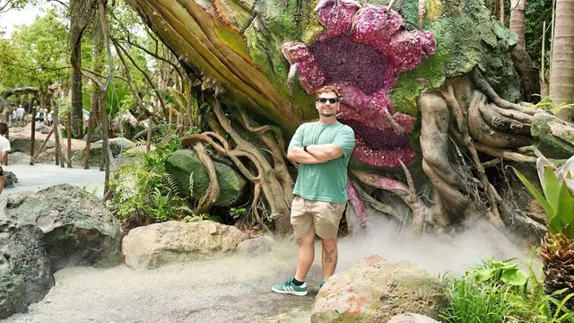 Thomaz de braços cruzados diante do tronco e da flor gigante de Pandora, com névoa, no Animal Kingdom