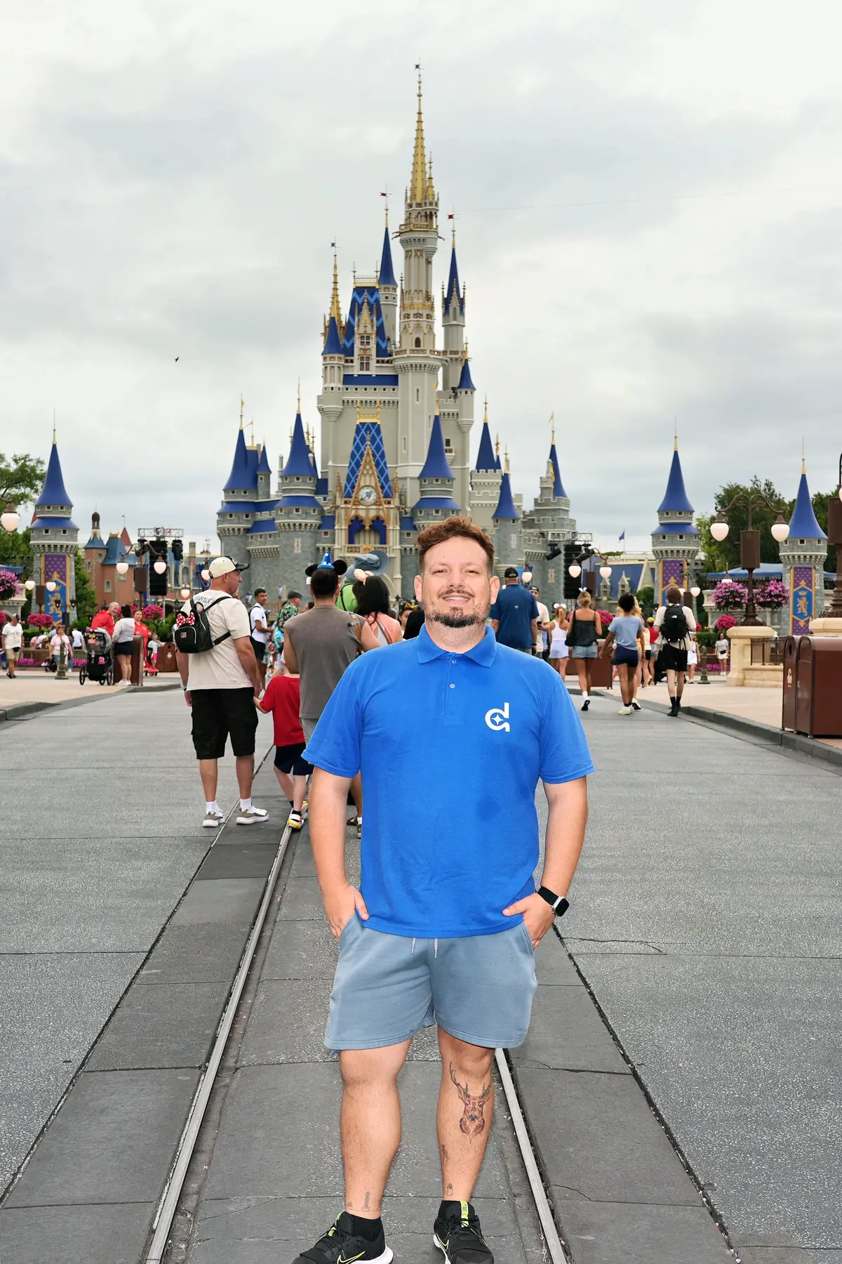 Thomaz, de camisa polo da Desenrola, nos trilhos da Main Street, com o Castelo da Cinderela ao fundo, no Magic Kingdom