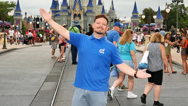 Thomaz, da Desenrola, de braços abertos nos trilhos da Main Street do Magic Kingdom, com o castelo ao fundo