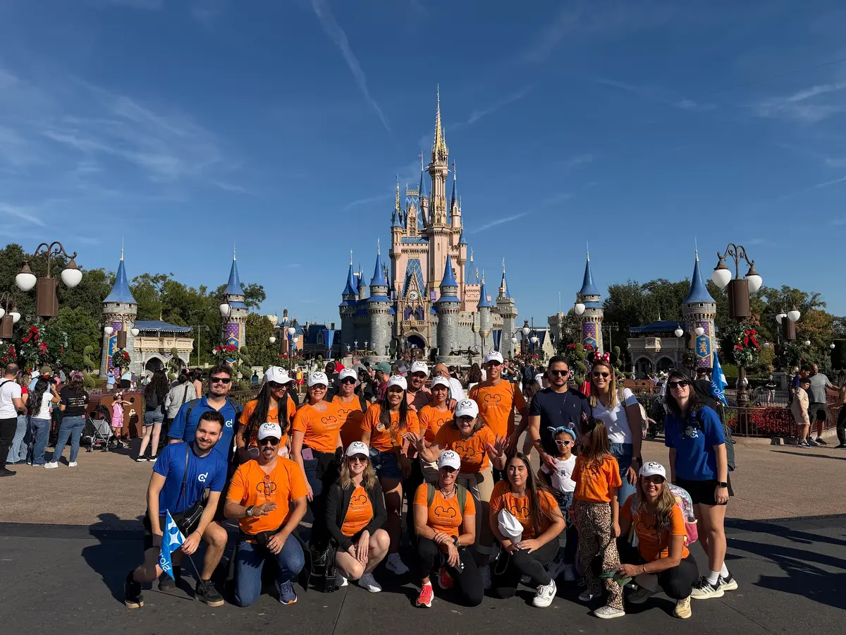 Grupo de viajantes com camisetas laranja posa diante do Castelo da Cinderela, no Magic Kingdom