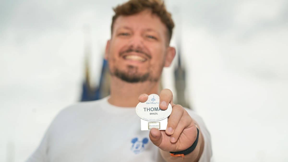 Thomaz, ex-cast member da Disney, mostra o crachá com seu nome diante do Castelo da Cinderela, no Magic Kingdom