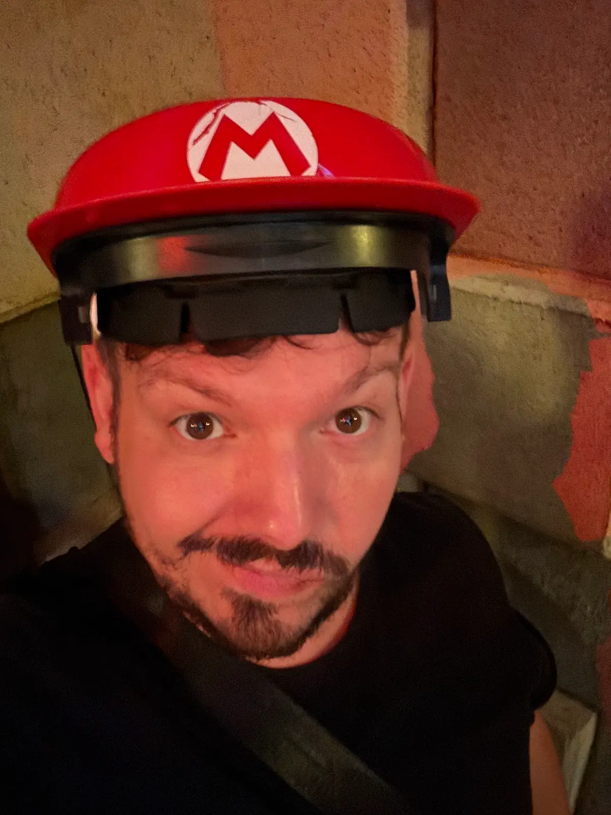 Selfie de Thomaz com o boné e o visor do Mario Kart: Bowser's Challenge, no Super Nintendo World do Epic Universe