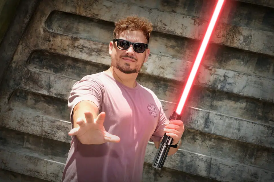 Thomaz com sabre de luz vermelho fazendo gesto da Força em parede de Star Wars, no Hollywood Studios