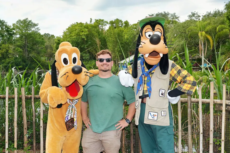 Thomaz com Pluto e Pateta em trajes de safári num encontro com personagens ao ar livre